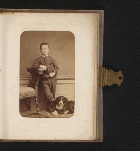 Portrait of a boy leaning on a chair with a dog at his feet