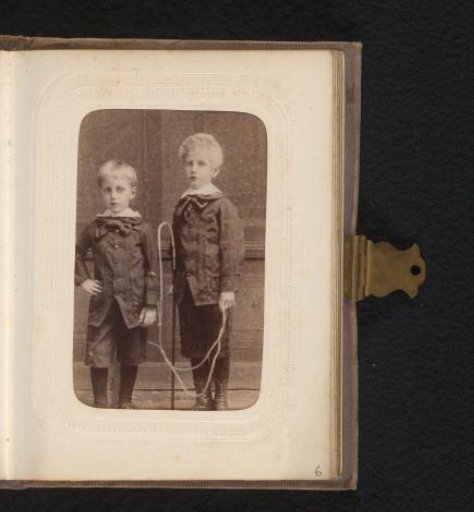 Portrait of two boys, one holding a whip
