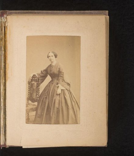 Portrait of a woman, standing by a chair