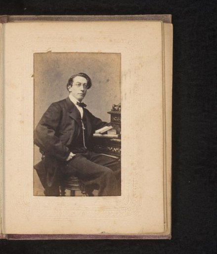 Portrait of a man with spectacles, seated at a desk