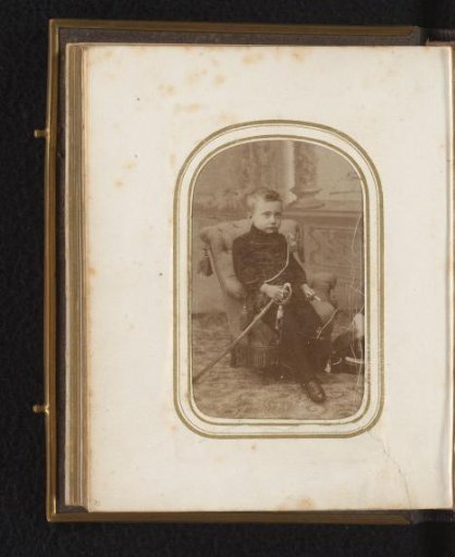 Portrait of a boy seated on a chair with a cigarette and a sabre in his hands