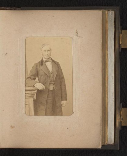 Portrait of a man, standing by a pedestal