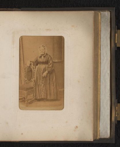 Portrait of a woman with a cap, standing by a chair