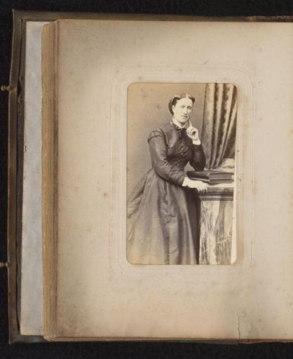 Portrait of a woman leaning on a pedestal with books