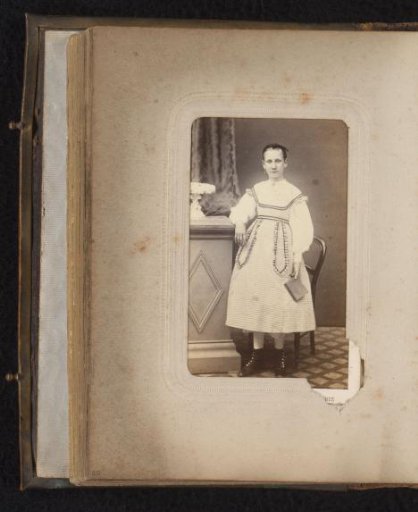 Portrait of a girl with a book in her hand, standing by a pedestal
