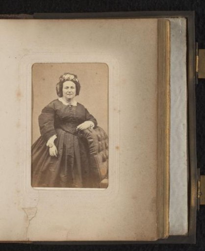 Portrait of a woman with flowers in her hair, standing by a chair