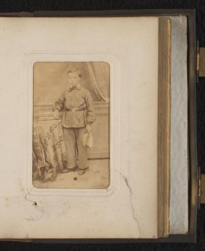 Portrait of a boy standing by a table with books
