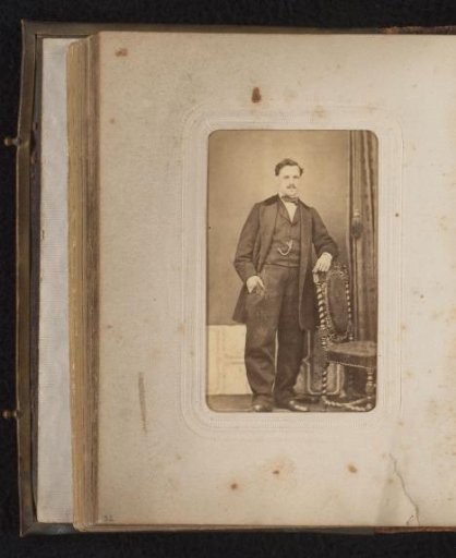 Portrait of a man standing by a chair