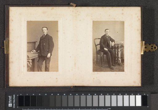 Portrait of a man in a short jacket, standing with a hand on a book