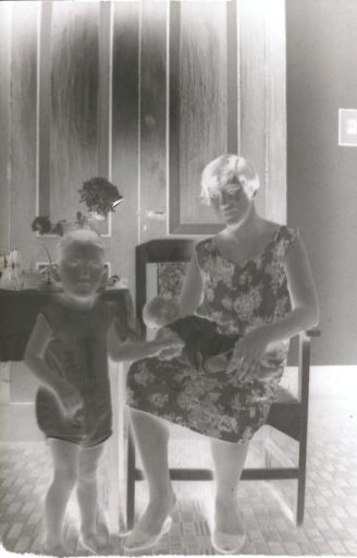 Young child standing beside a woman seated in a chair