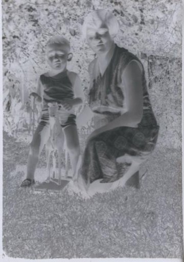 Woman and child with a toy horse on a grassy field