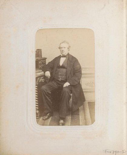 Portrait of a man in a coat, seated at a desk