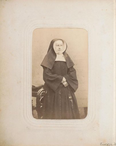 Portrait of a standing nun with a veil and a rosary in her hand