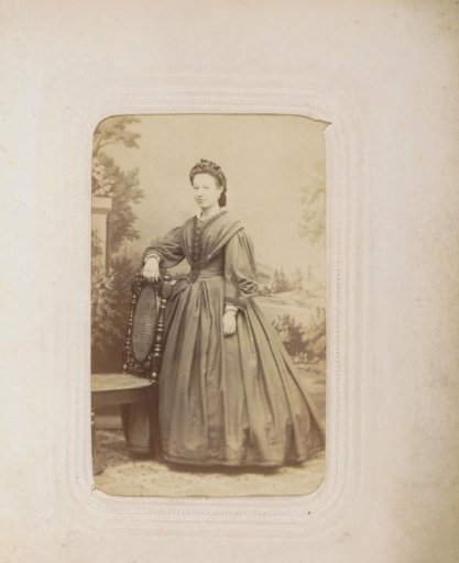 Portrait of a woman in a long dress, standing before a landscape backdrop