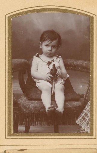 Portrait of a sitting toddler with a toy bird in hand