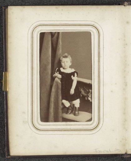 Portrait of a toddler in a dress, standing on a chair