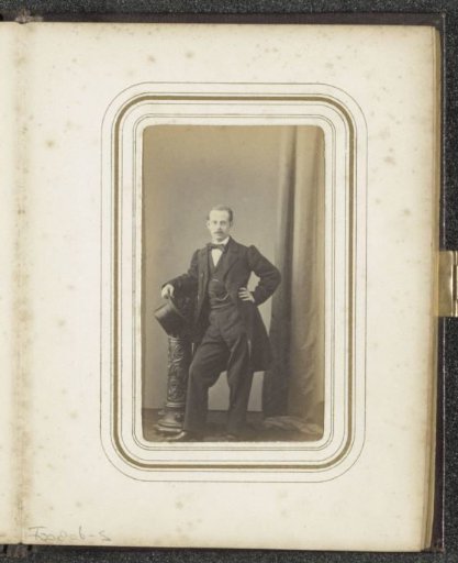 Portrait of a man with a tall hat standing by a pedestal