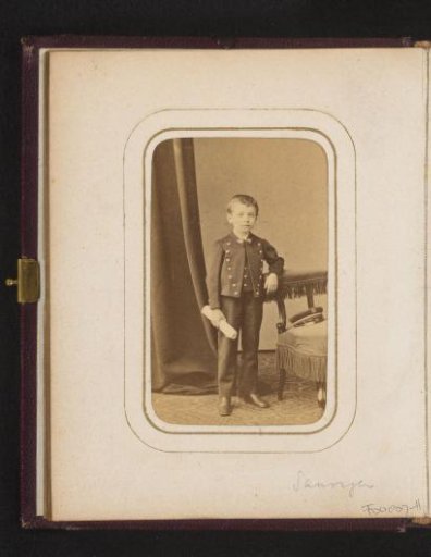 Portrait of a standing boy with a roll of paper in his hand
