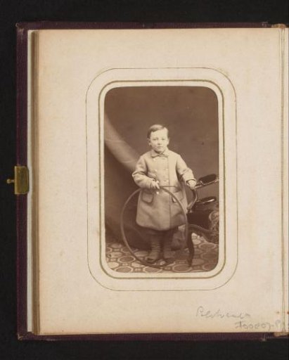 Portrait of a boy with a hoop, standing by a chair