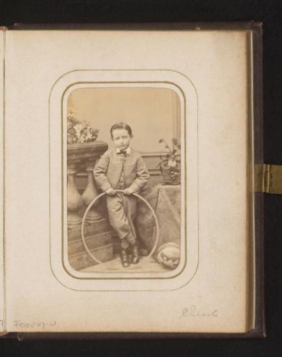 Portrait of a boy with a hoop in his hand, standing by a balustrade