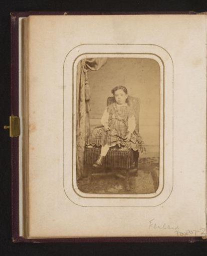 Portrait of a girl in a checkered dress, sitting on a chair