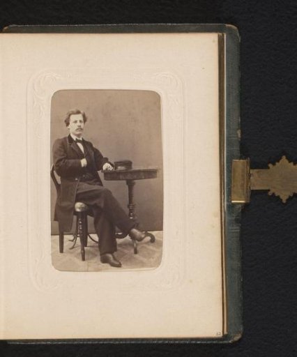 Portrait of a man seated at a table with a cap on it