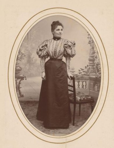 Portrait of a Woman Standing by a Chair in a Setting
