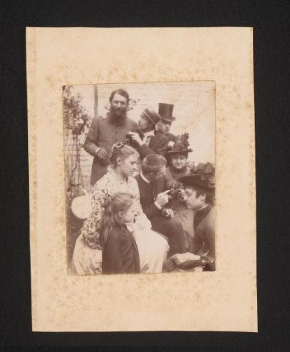 Four Men, Three Women, and a Girl in Festive Attire in a Garden