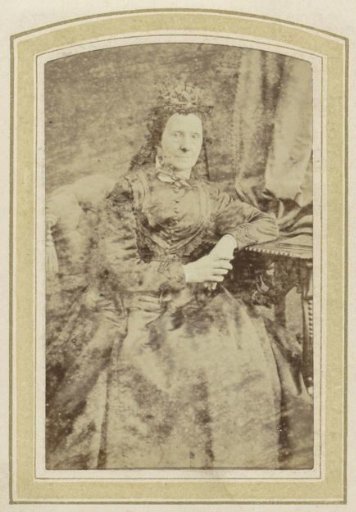 Portrait of an old woman in a dress at a table