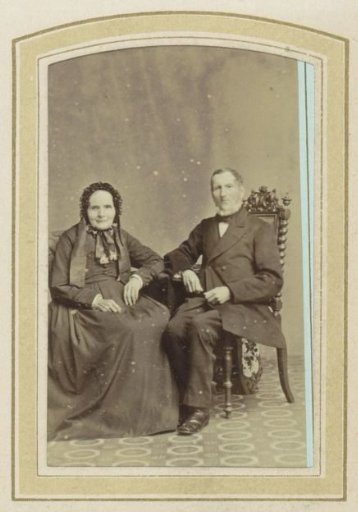 Portrait of a woman in a dress with a headdress and a seated man