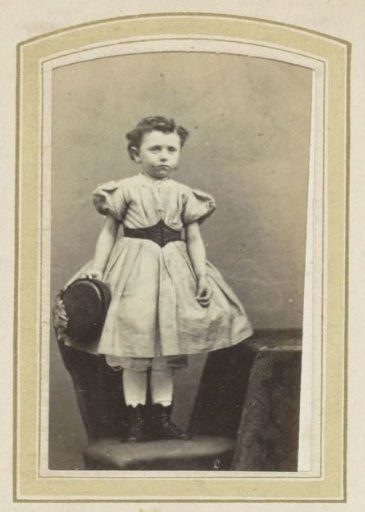Portrait of a girl in a dress with a sash on a chair