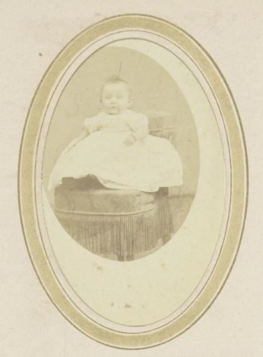Portrait of a baby in a dress on an armchair