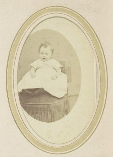 Portrait of a baby in a dress on an armchair