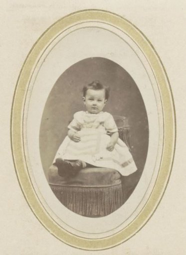 Portrait of a toddler in a striped dress on an armchair