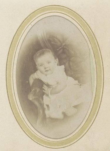 Portrait of a baby in a dress on an armchair