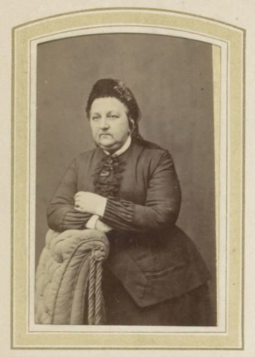 Portrait of a woman with a cap leaning on an armchair