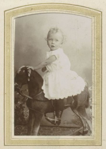 Portrait of a Toddler in a Dress on a Rocking Horse