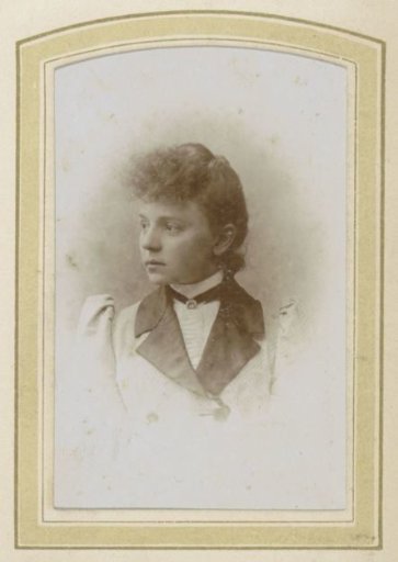 Portrait of a young woman with her hair up, a necklace and a coat with wide lapels