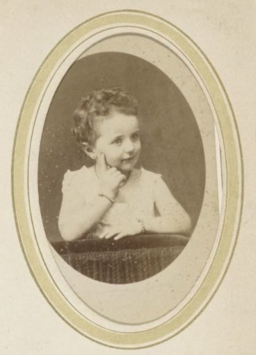 Portrait of a young child with two bracelets, holding a finger to the cheek