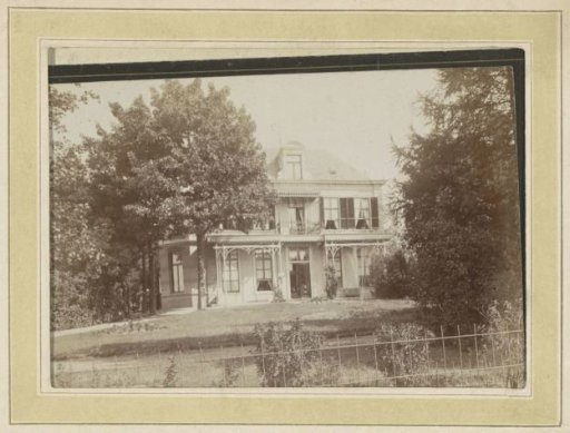 Exterior of a villa with veranda and front garden behind a fence