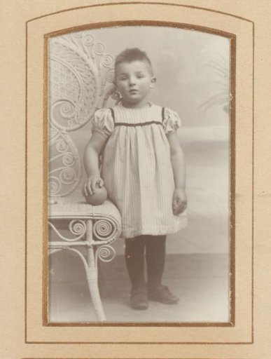 Portrait of a boy, standing by a chair with a ball
