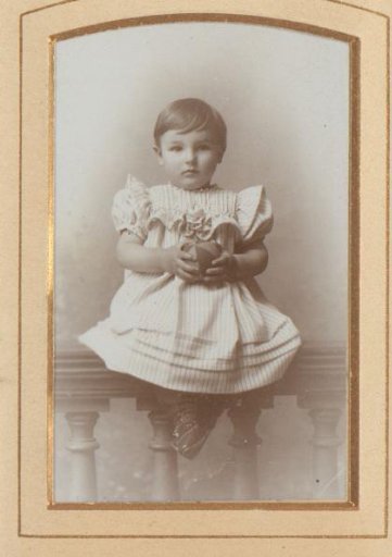 Portrait of a girl, seated on a balustrade with a ball