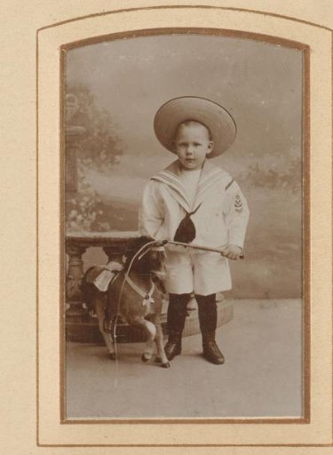 Portrait of a boy with a hobby horse and hat