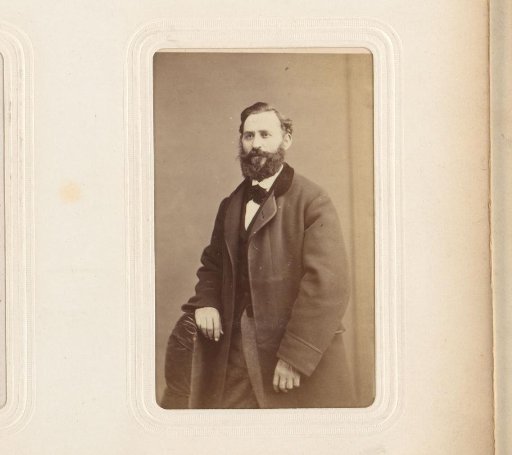Portrait of a man with a beard, standing next to a chair