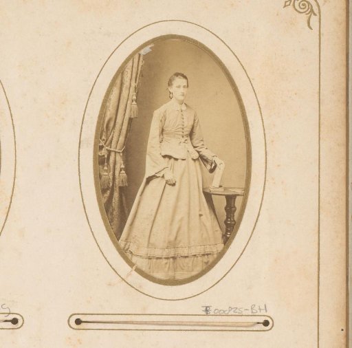 Portrait of a young woman holding a book, standing by a table