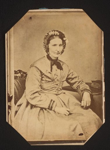 Portrait of a woman with a cap, seated at a table