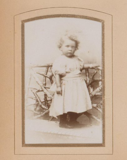 Portrait of a Girl Standing by a Fence