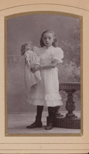 Portrait of a Standing Girl Holding a Doll