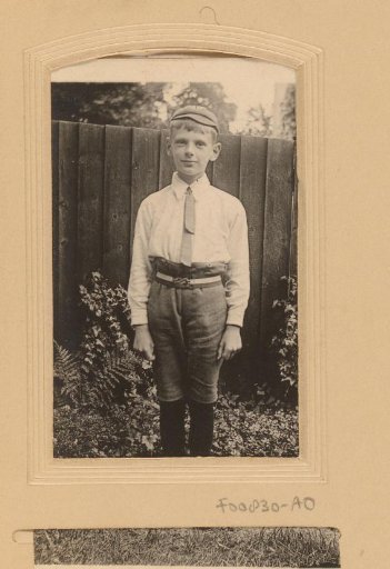 Portrait of a standing boy with cap and tie in the garden