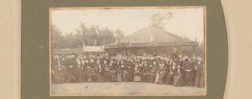 Group portrait of a party at the fair in front of a Steam Bicycle tent